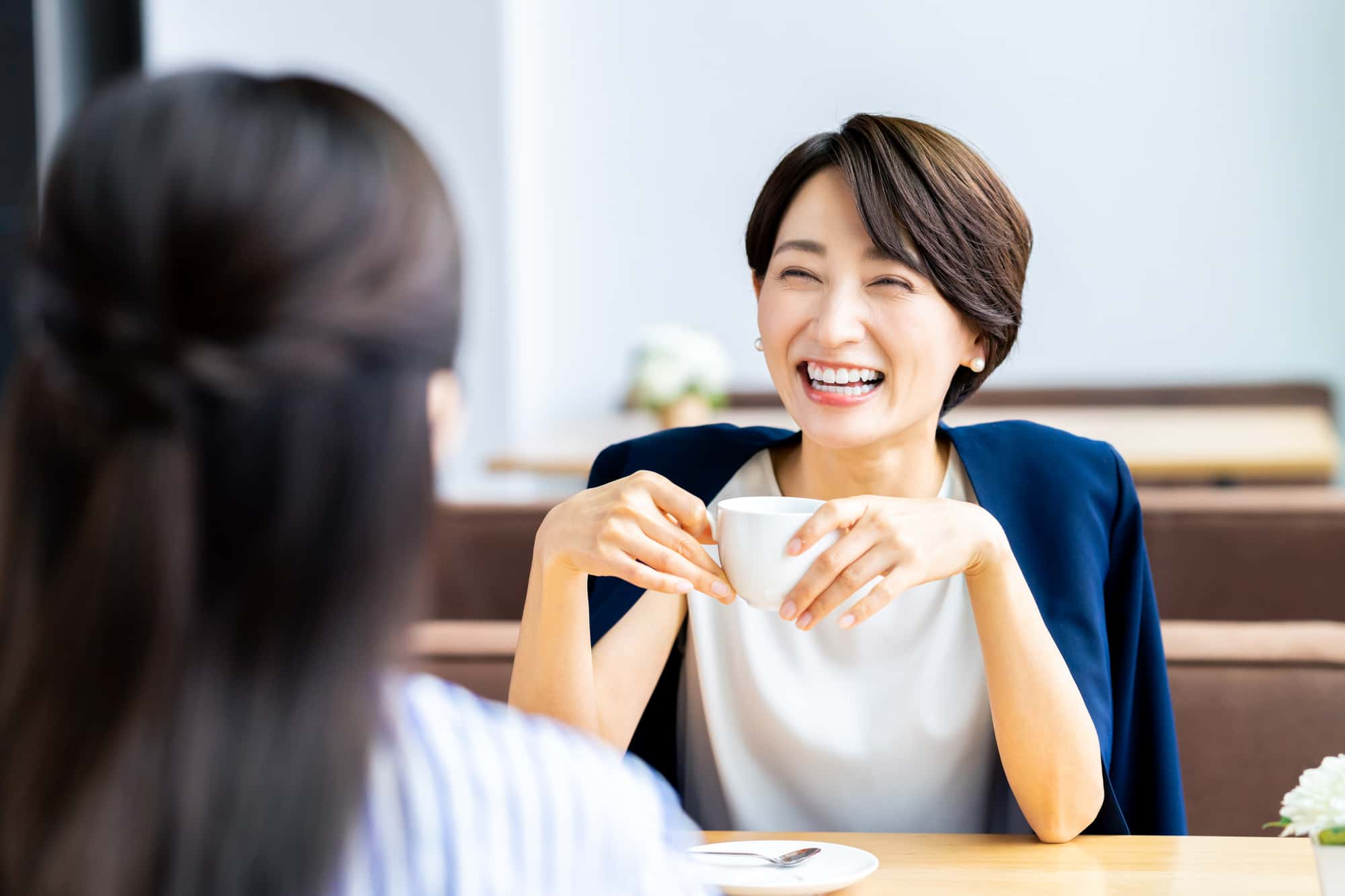 ホワイトニングで綺麗になった歯で友人と会話する女性