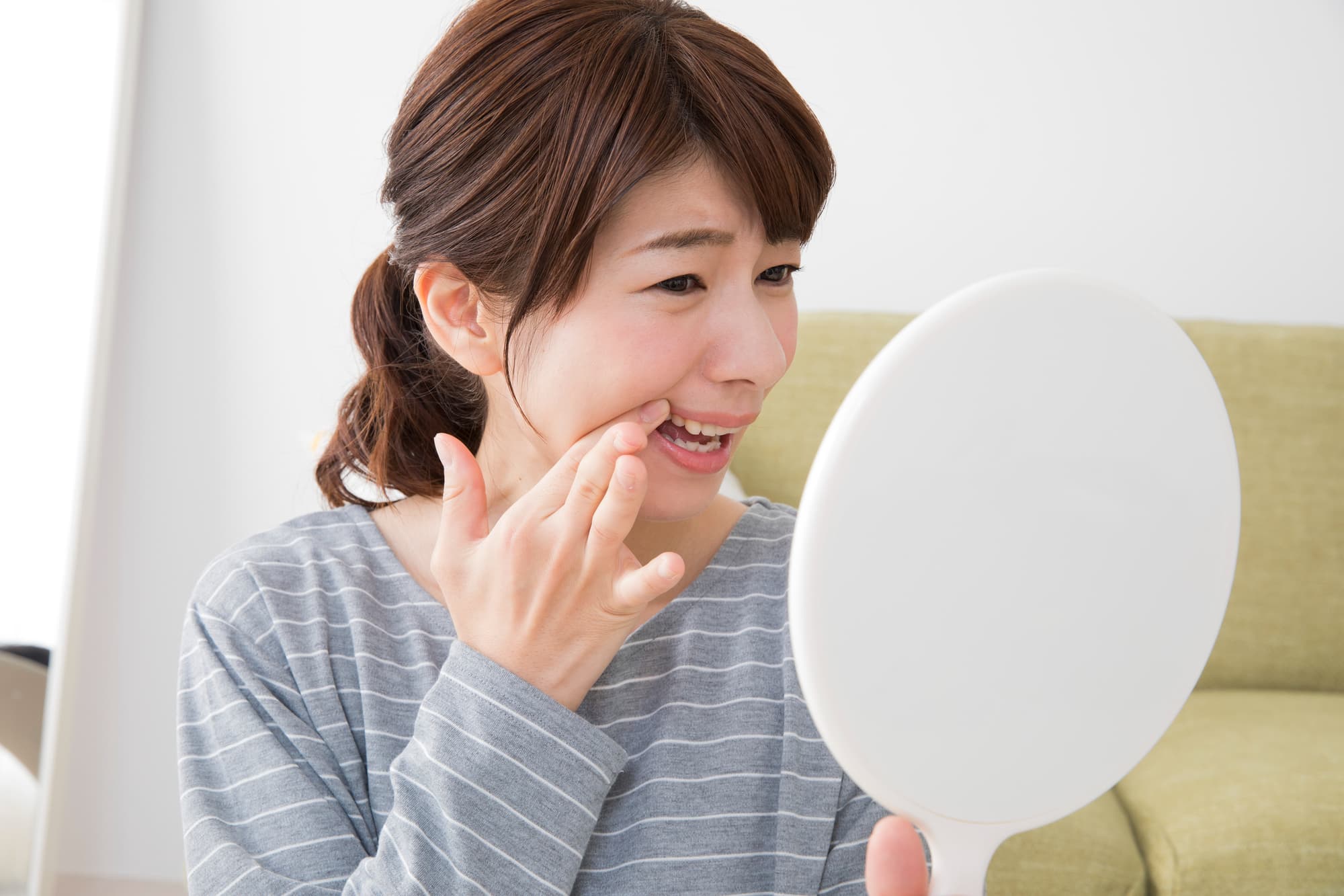 歯茎が気になり鏡で確認する女性