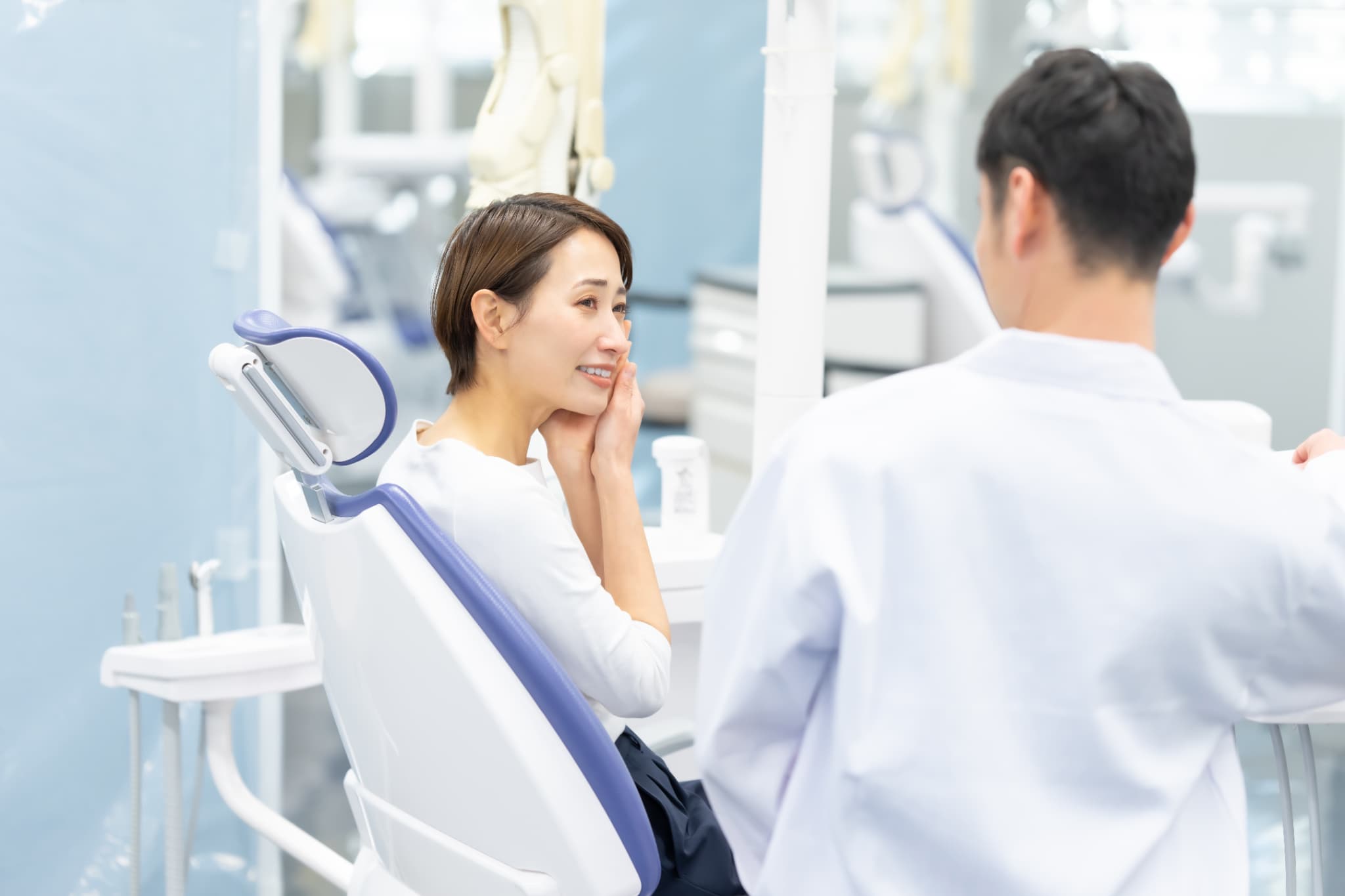 インプラント治療は痛いのか不安な女性と説明する歯科医師