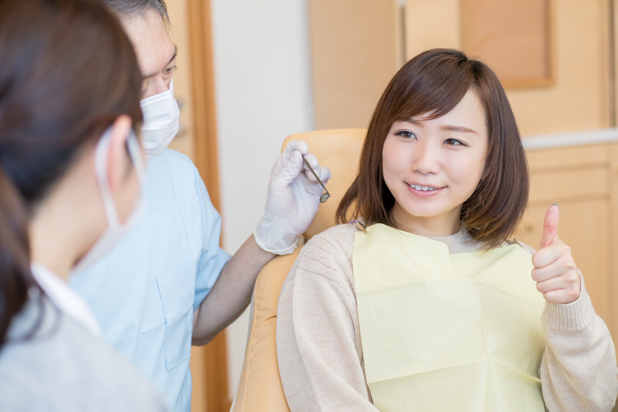 親知らずの虫歯を治療してグーサインを出す女性