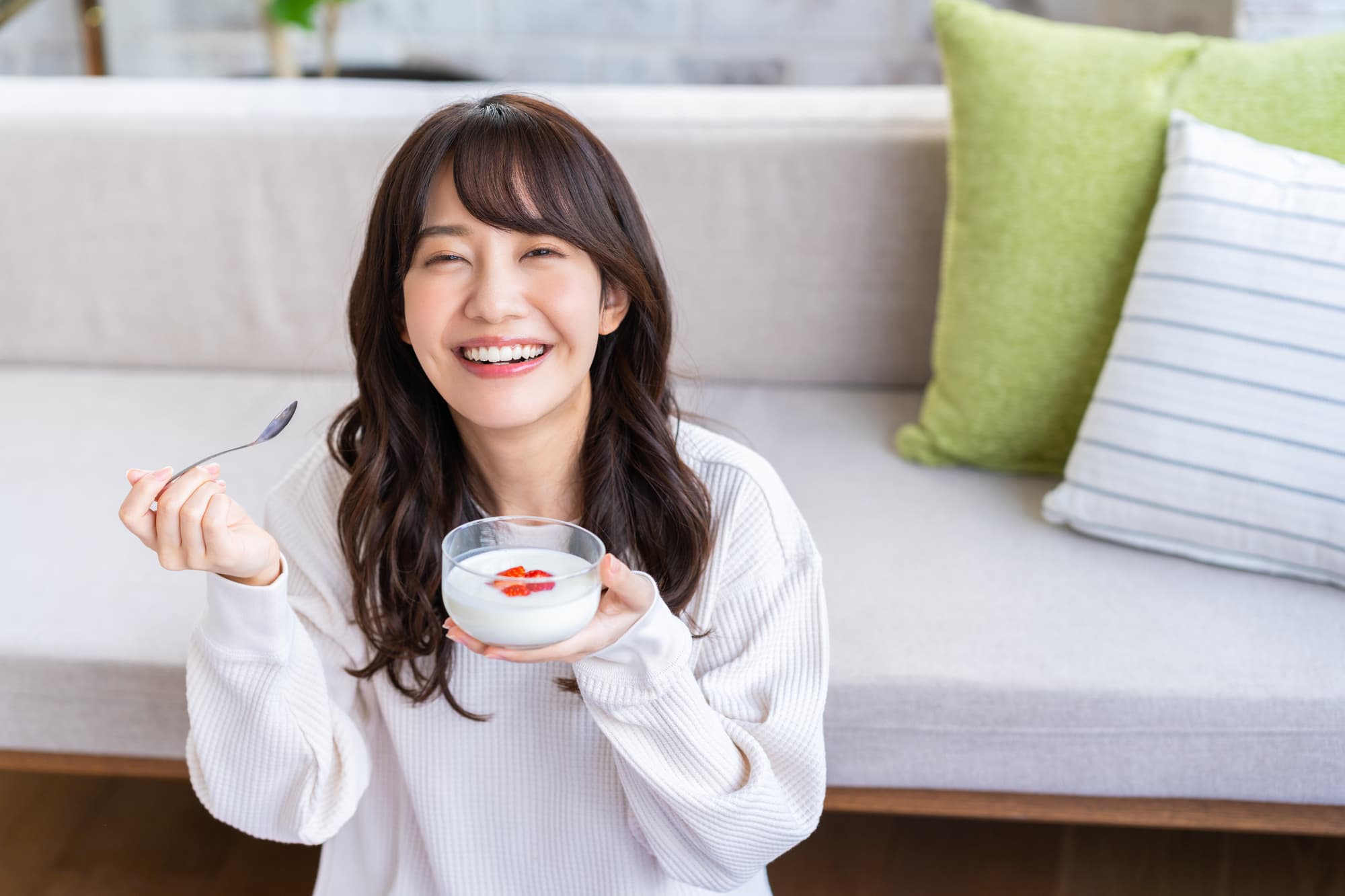 ヨーグルトを食べる笑顔の女性
