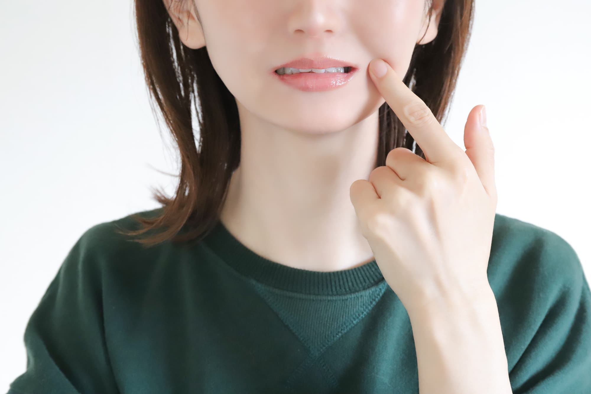 食いしばりの口元を指さす女性